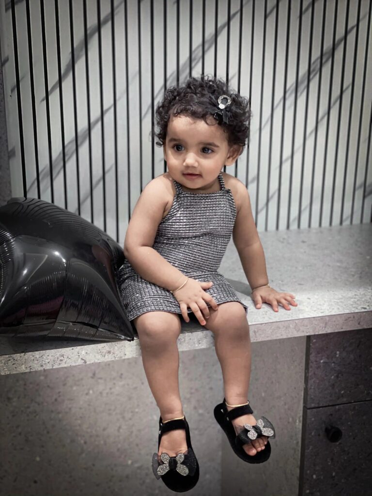A little baby girl wearing grey bodycon dress captured by best wedding photography in Calicut,